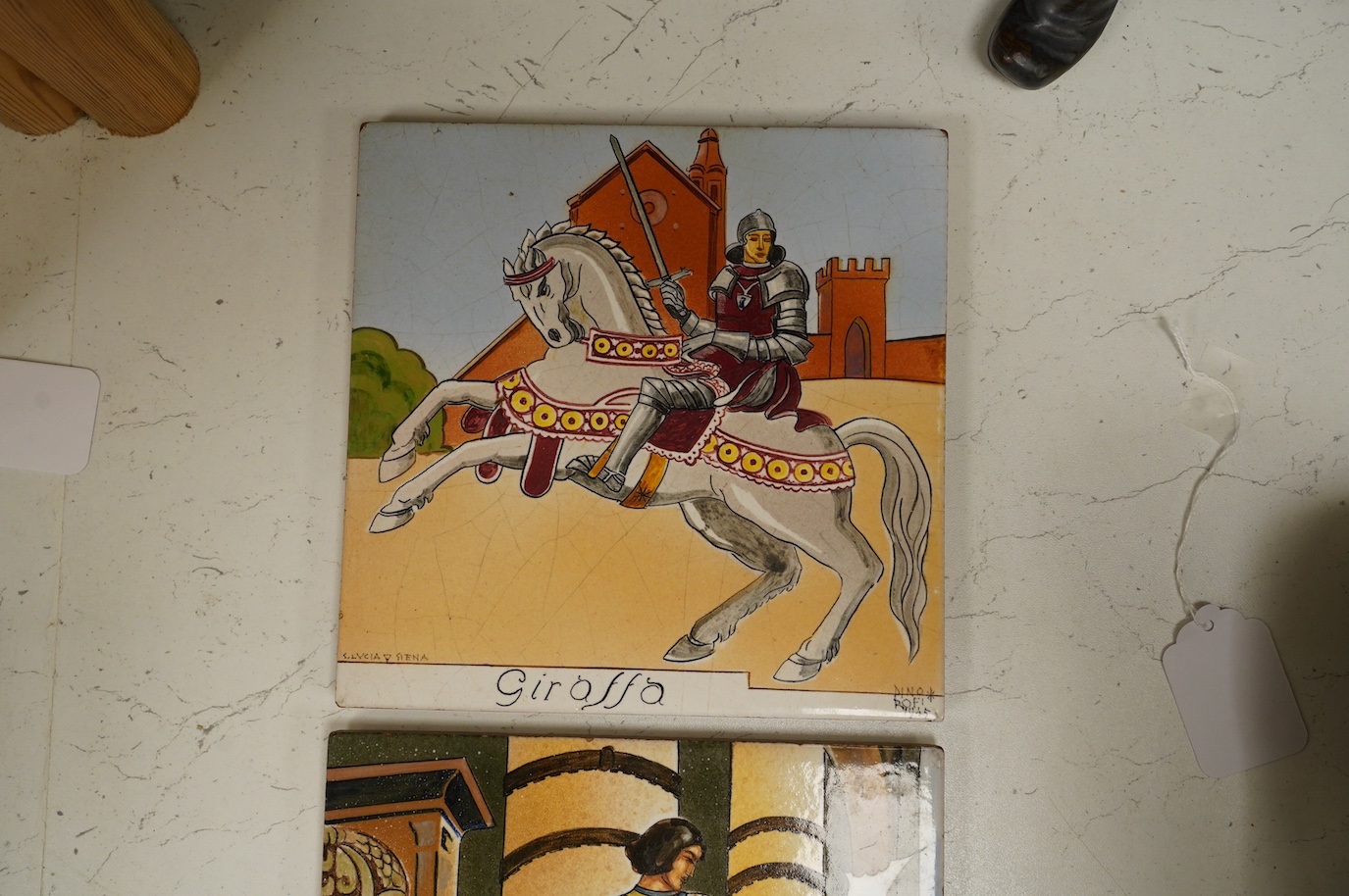 Dino Rofi, two S. Lucia, Sienna maiolica tiles, dated 1944 and 1945, decorated with Medieval scenes of warriors, 20 x 20cm. Condition - good